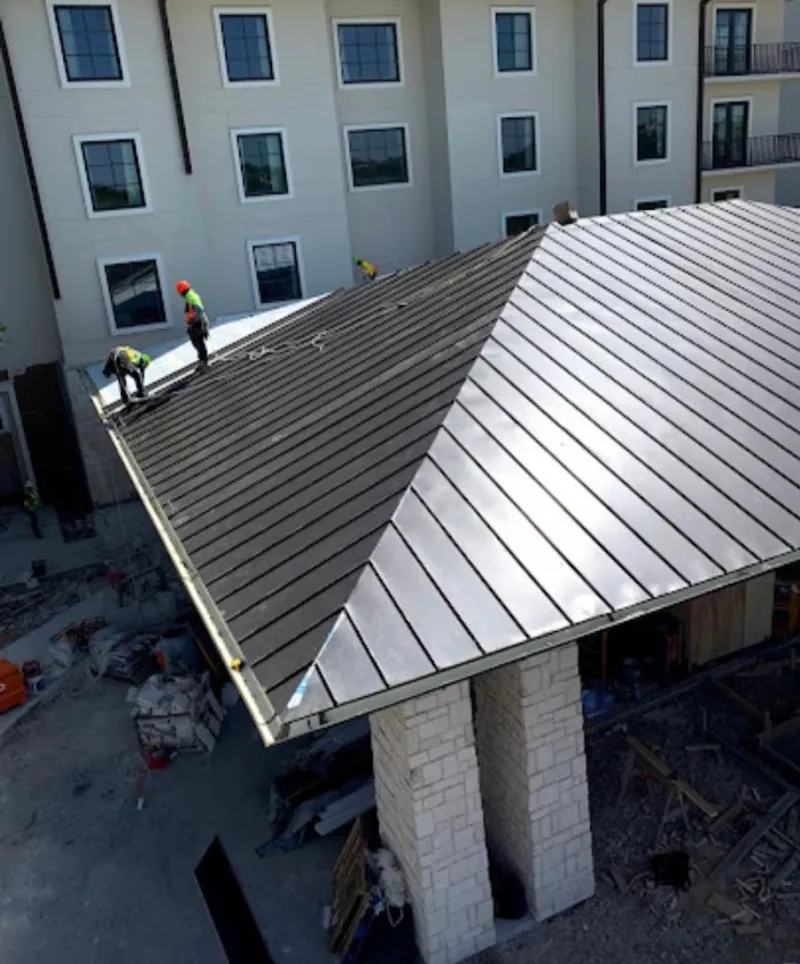 Crew installing standing seam metal roof panels on a commercial project in LaGrange